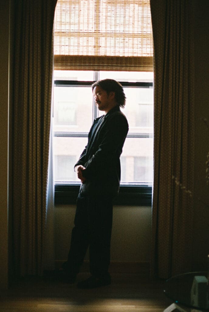 Groom smiling in a silhouette, window-lit frame getting ready at the Proper Hotel in DTLA.